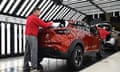 Man in red jumper polishes back of red car