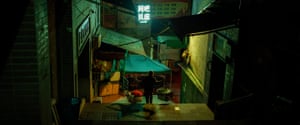 Mountain City, Chongqing, 03:45:55Chongqing after dark - A market worker balancing goods on a bamboo pole, making her way through the backstreets of Chongqing - known as the Mountain City.