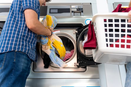 Young couple loading clothes into washing machine in a laundry