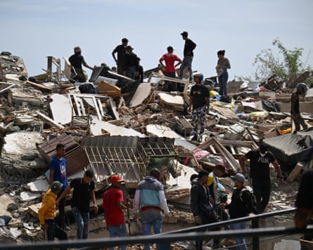 People search through a large mound of rubble
