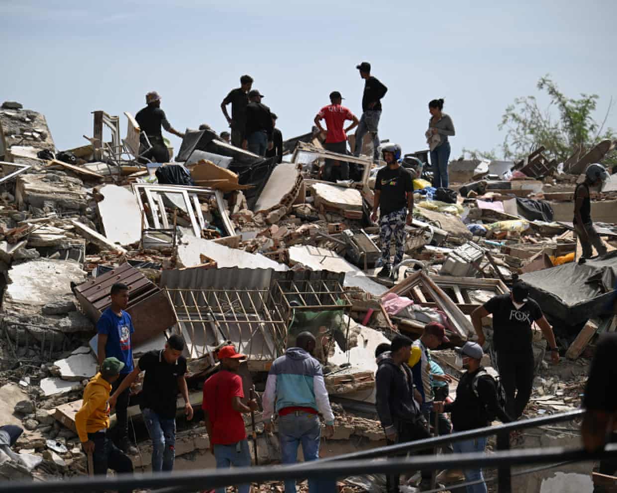 People search through a large mound of rubble