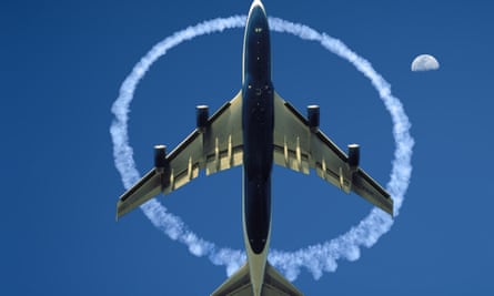 picture of a plane from below surrounded by a circle of contrails in the blue sky with the moon seen to the right