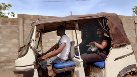 Two women riding in the back of a tuk-tuk