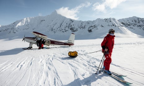 Griffin Post on skis in front of a small plane between snowy mountains