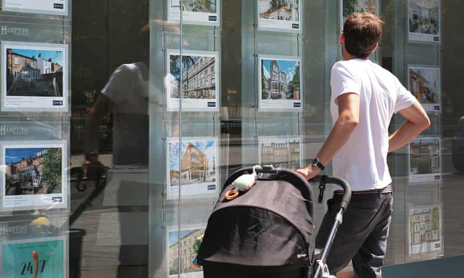 A young dad looking at houses in an estate agent's window