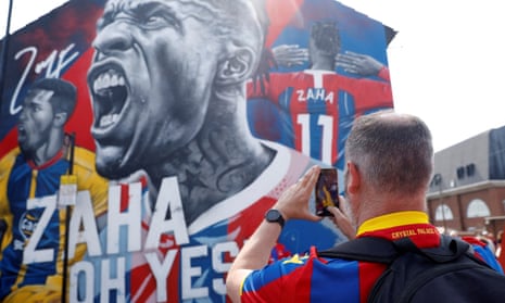 A Crystal Palace fan takes a photo of the Wilfried Zaha mural outside Selhurst Park.