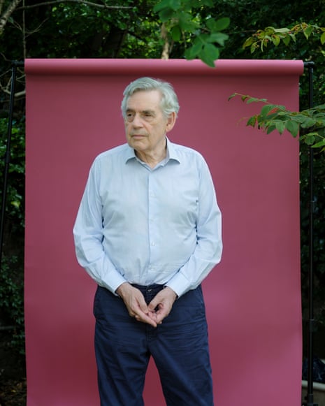 Headshot of British politician Gordon Brown in pale shirt against burgundy background