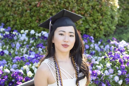 Asian woman with long hair wearing graduation cap and white dress