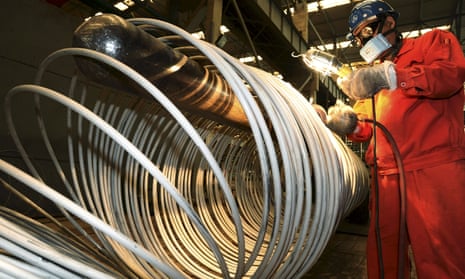 A worker polishes steel coils at a factory in Dalian in China.