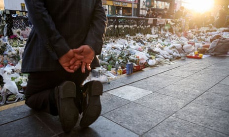 A mourner kneels next to floral tributes near the site of a crowd crush that happened during Halloween festivities, in Seoul.