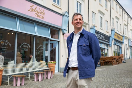 Sam Kirkness stands in front of a high street bakery