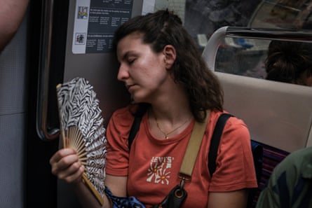 A passenger cools herself with a hand fan on the Paris Metro.