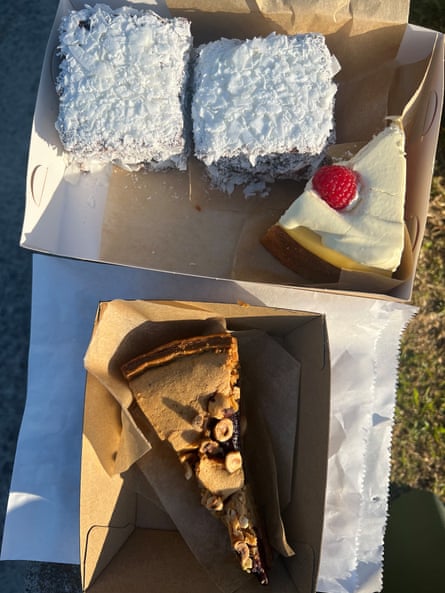 A selection of cakes and pastries in cardboard trays in the afternoon sun.