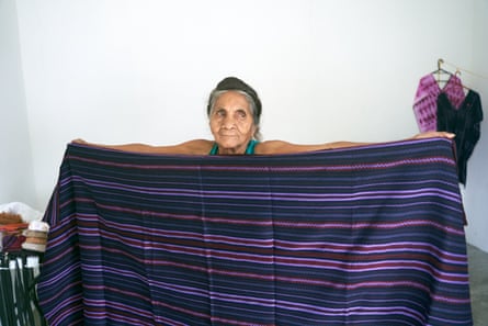 A woman holds up a striped, purple woven blanket