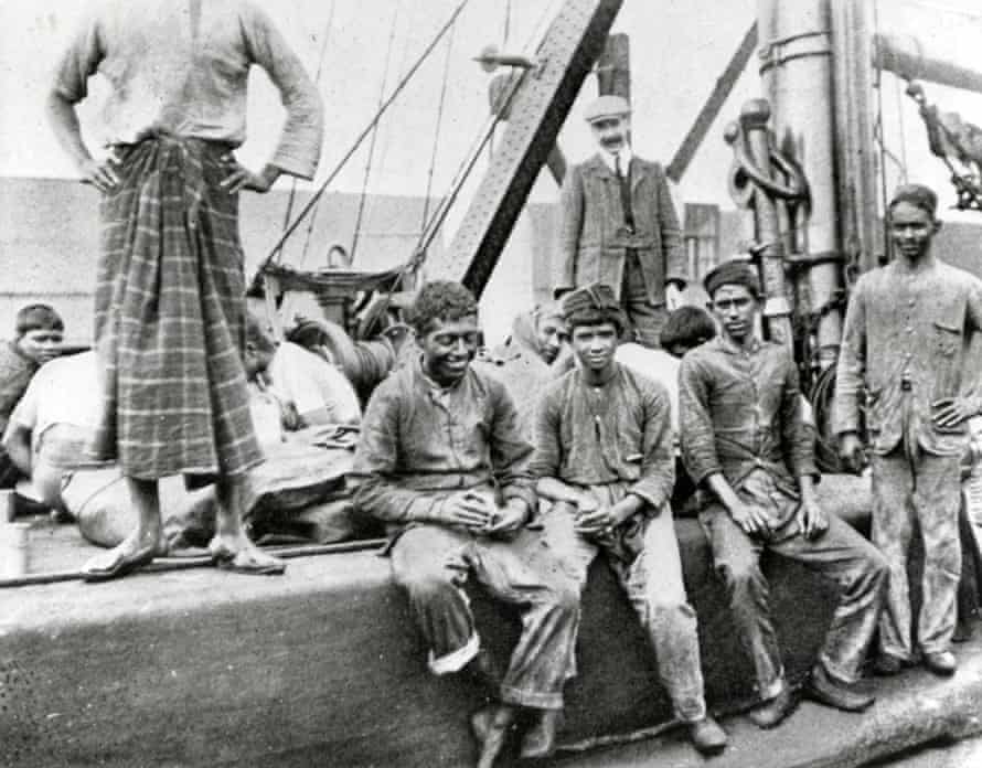 Men sitting and standing on a ship in dock.