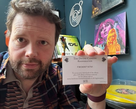 A man holds up a card offering a download of an album.