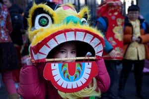 London, England, A young performer looks out of a dragon mask before the Lunar New Year parade to mark the arrival of the Year of the Rabbit