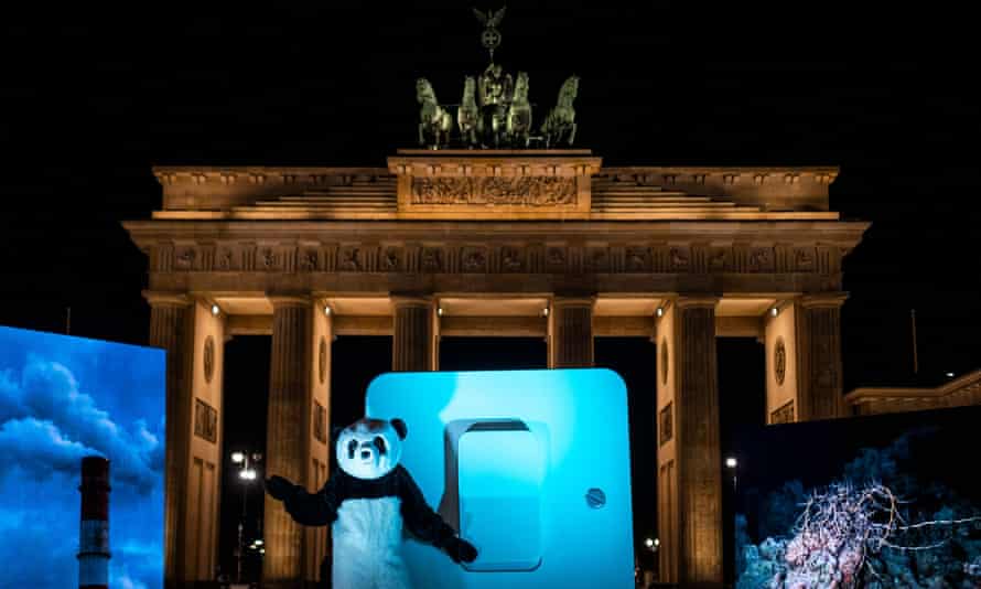 A WWF activist dressed in a Panda suit prepares to symbolically throw a giant switch to turn off the illumination of Berlin’s Brandenburg Gate.