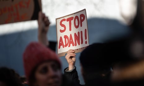 A hand holds up a 'Stop Adami' sign
