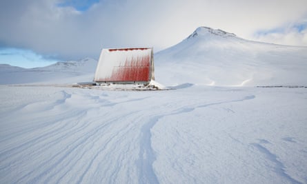 Mountain refuge hut in the deep snow in Iceland - with its tall red roof it stands out in the surroundings.