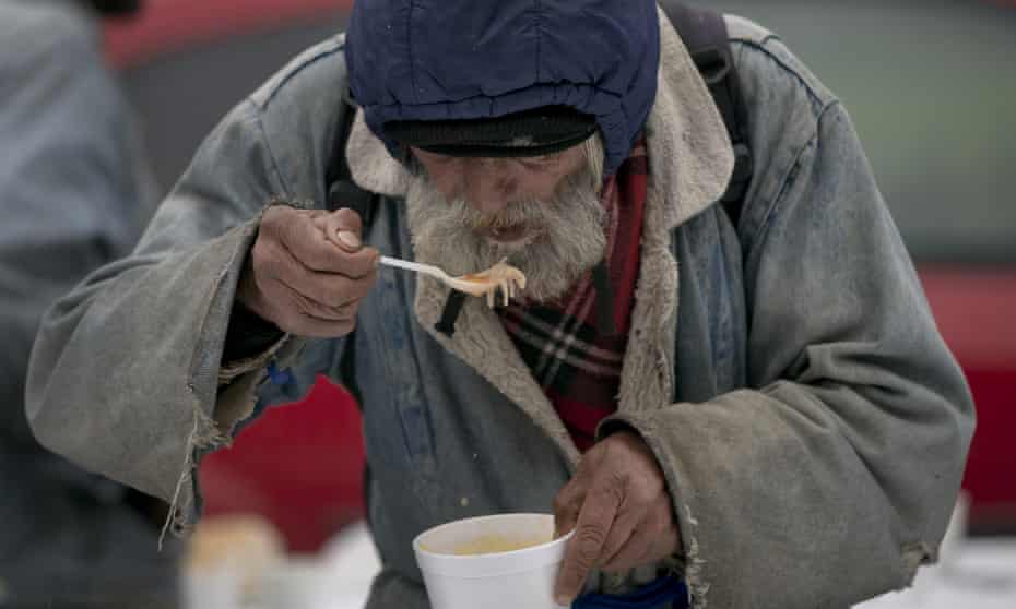 A homeless man eats soup received at a humanitarian event outside the main railway station in Bucharest, Romania
