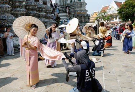 Tourists dressed in traditional Thai attire pose for souvenir photographs at the Wat Arun temple.