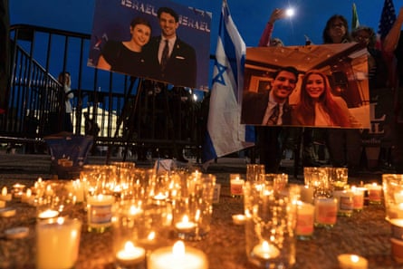 candles on the ground in front of an Israeli flag and two photos of a man and a woman
