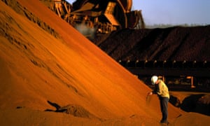A worker inspecting iron ore stockpiles
