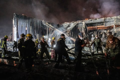 Rescue workers including firefighters work through the rubble of building during the night