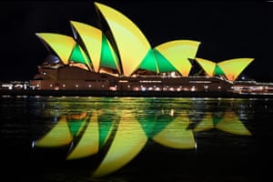 The Sydney Opera House illuminated in green and gold.
