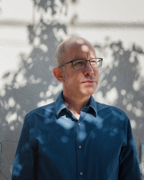 a man in glasses and a collared shirt looks into the distance