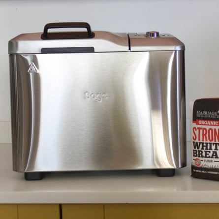 A stainless steel Sage bread maker with a dark handle sits beside a flour bag