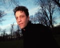 A man with short brown hair looking into the camera with trees and sky behind him