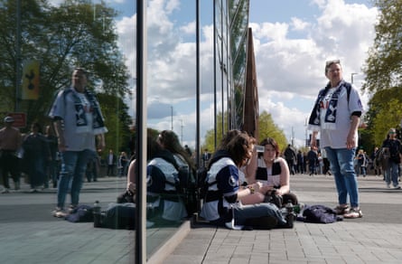 Spurs fans sit on the pavement outside the main entrance to the stadium