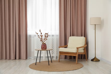 Living room with pastel curtains, wooden table and armchair