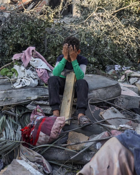 A boy sitting with head in hands amid the rubble of a house destroyed in an Israeli strike in Nuseirat