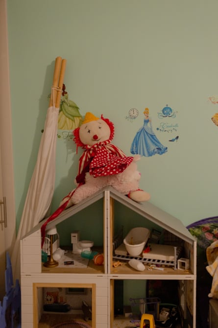 a stuffed animal sits atop a dollhouse in a children’s green bedroom