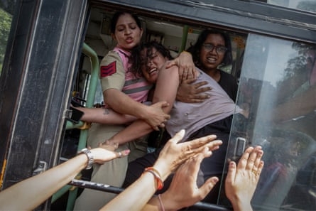 Police try to stop a detained protestor to escape from a bus during a protest by the Cockroach Janta party