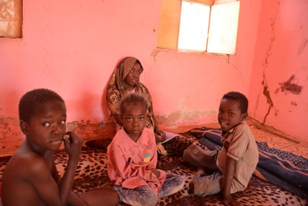 Four young African children – two boys and two girls – sit in an empty room
