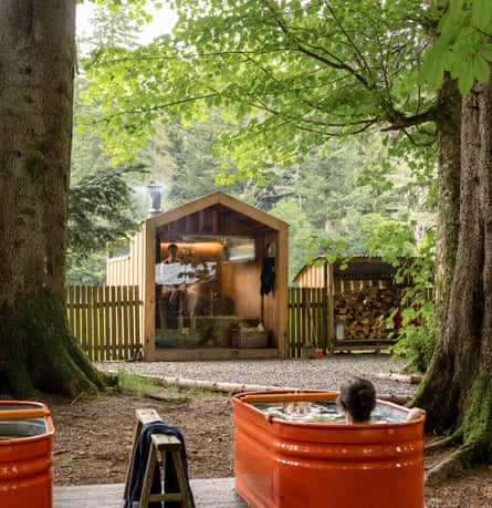 Two hot tubs painted red under trees with sauna cabin beyond on the Glen Dye estate.