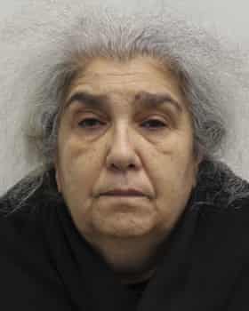 Mugshot of a woman with grey hair and wearing black