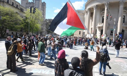 person waves Palestinian flag in front of grand building