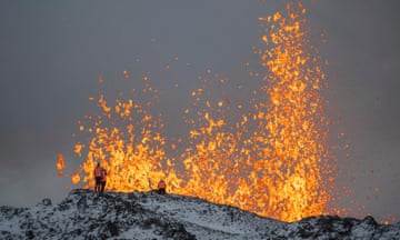 Scientists stand on a ridge in front of the active volcano on Reykjanes peninsula.