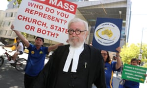 Robert Richter with people displaying placards behind him