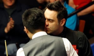 Ronnie O’Sullivan, right, shares a hug and a kiss withDing Junhui after his world championship quarter-final defeat at the Crucible.