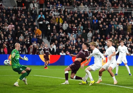 Oisin McEntee scores, kicking the ball past a diving goalkeeper during a football match