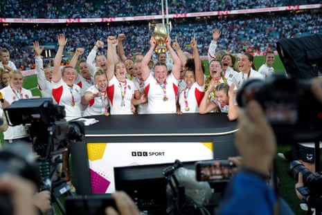 The victorious England team, led by the prop Sarah Bern with the trophy, storm the BBC’s pitch-side studio.