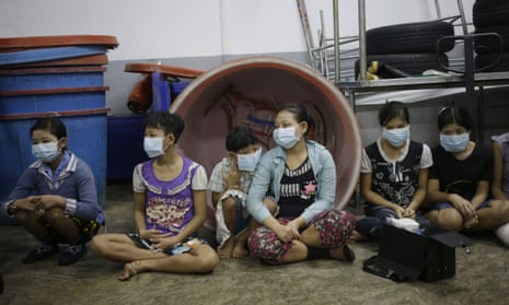Children and teenagers wait to be registered by officials during raid on a shrimp shed in Samut Sakhon, Thailand