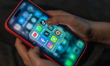 A person looks at an iPhone screen showing various social media apps including TikTok, Facebook and X