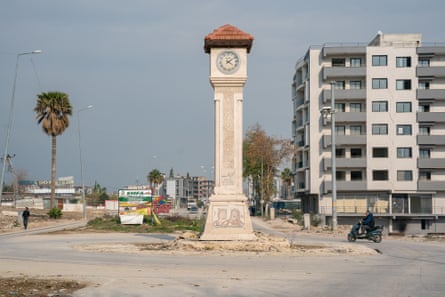 A clock tower standing on its own in an empty square
